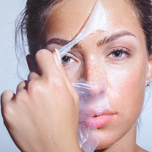 Close-up beauty portrait of a beautiful, natural young woman removing face mask. Copy space has been left